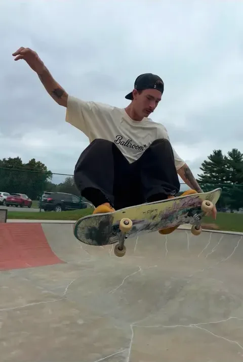 Trenton grabbing air over a skatepark ramp in the Ballroom tee