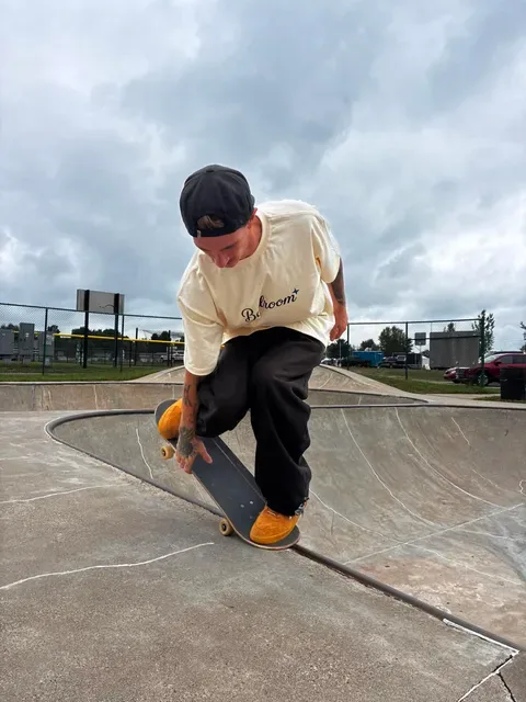 Trenton crouched and grabbing his board on the edge of a skatepark bowl