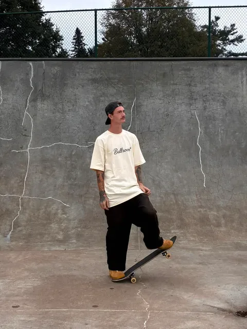 Trenton standing with one foot on his board against a cracked concrete bowl wall